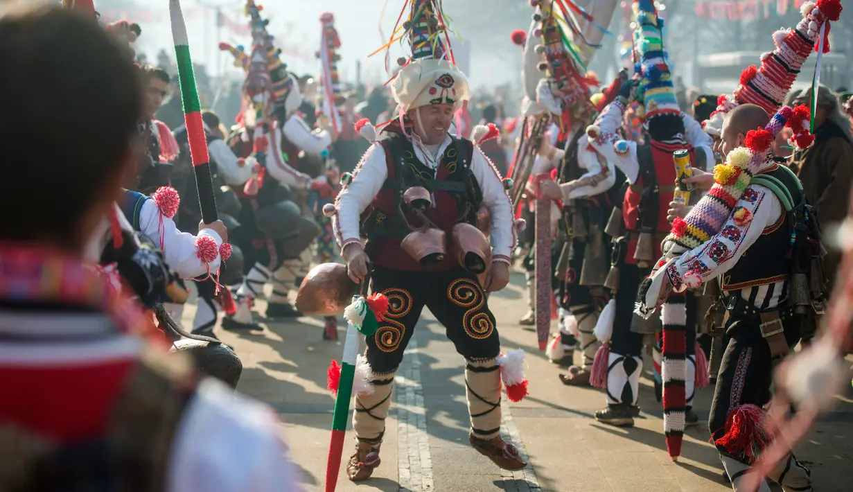 Seorang penari atau "Kukeri" melakukan gerakan tarian saat mengikuti Festival Internasional Masquerade Games di Pernik, Bulgaria (28/1). Para peserta mengenakan topeng dan aksesoris yang dipenuhi manik-manik dan pita. (AFP/Nikolay Doychinov)
