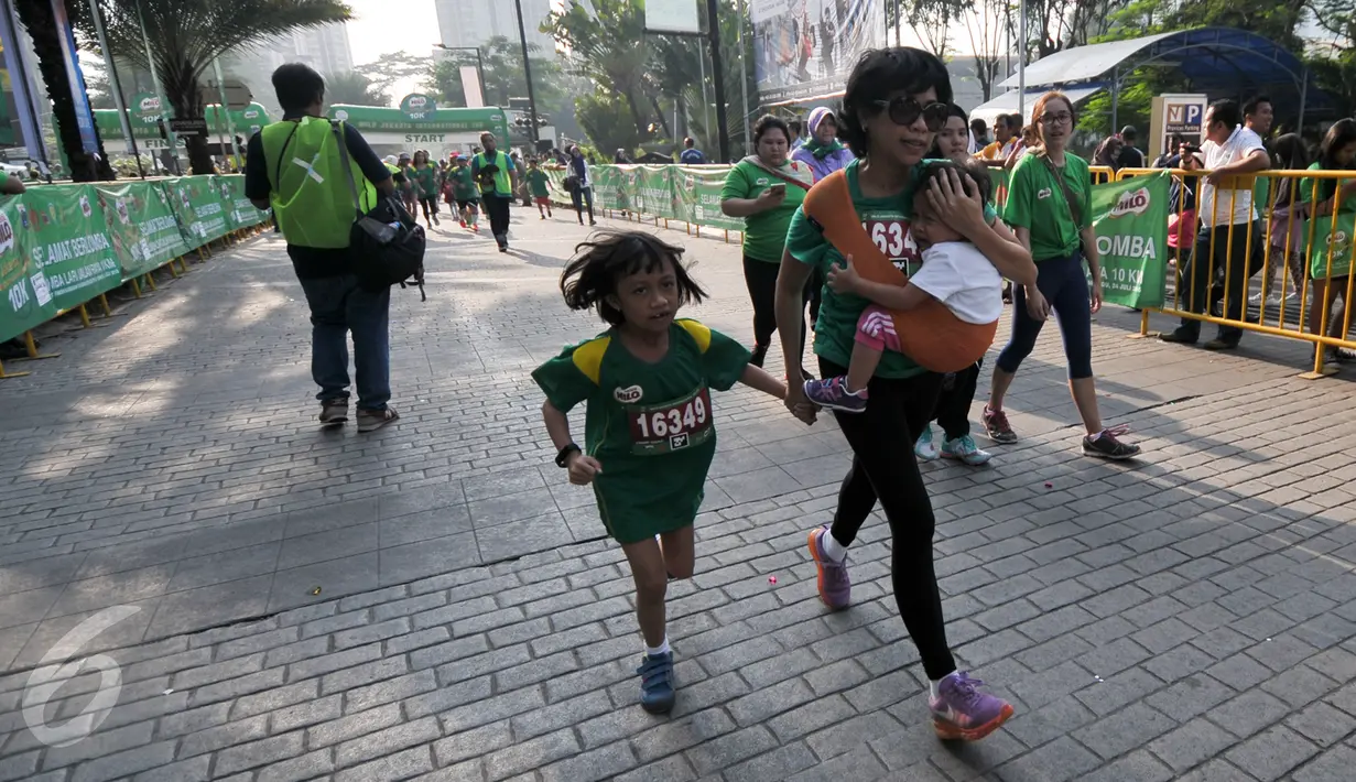 Seorang ibu menggendong anaknya sambil mengikuti lomba Milo Champ Squad Run di area Rasuna Said, Kuningan, Jakarta, Minggu (24/7). (Liputan6.com/Yoppy Renato)