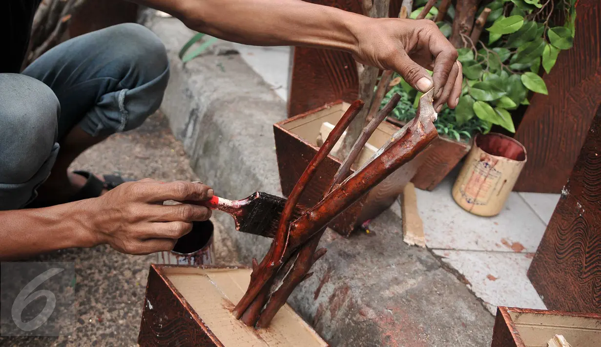 Pengrajin mengecat bagian bawah Pohon Hias Imlek di kawasan Glodok, Jakarta, Kamis (21/1/2016). Penjual Pohon Hias Imlek mengaku kebanjiran order jelang perayaan Imlek. (Liputan6.com/Gempur M Surya)