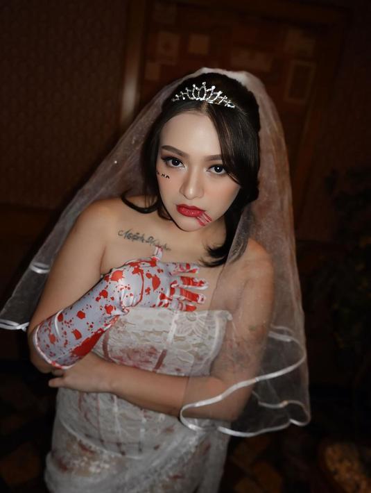 Sentuhan make-up berdarah di bagian mulut dan sarung tangan berlumuran darah menjadi elemen yang semakin mempertegas kesan seram pada penampilannya. Gaun yang transparan dengan aksen sobekan menambah aura mencekam. (Liputan6.com/IG/@nathalieholscher)
