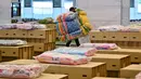 Pekerja menyiapkan kasur dan selimut untuk tempat tidur kardus di rumah sakit lapangan Covid-19 di dalam gudang Bandara Internasional Don Mueang di Bangkok, Selasa (27/7/2021). Thailand menghadapi rekor jumlah kasus virus corona di tengah kampanye vaksinasi yang lambat. (Lillian SUWANRUMPHA/AFP)