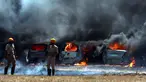 Petugas pemadam kebakaran berdiri dekat deretan mobil yang terbakar di area parkir pameran dirgantara Aero India 2019, Bangalore, India, Sabtu (23/2). Api melahap sekitar 300 mobil. (AP Photo/Parthi Bhan)