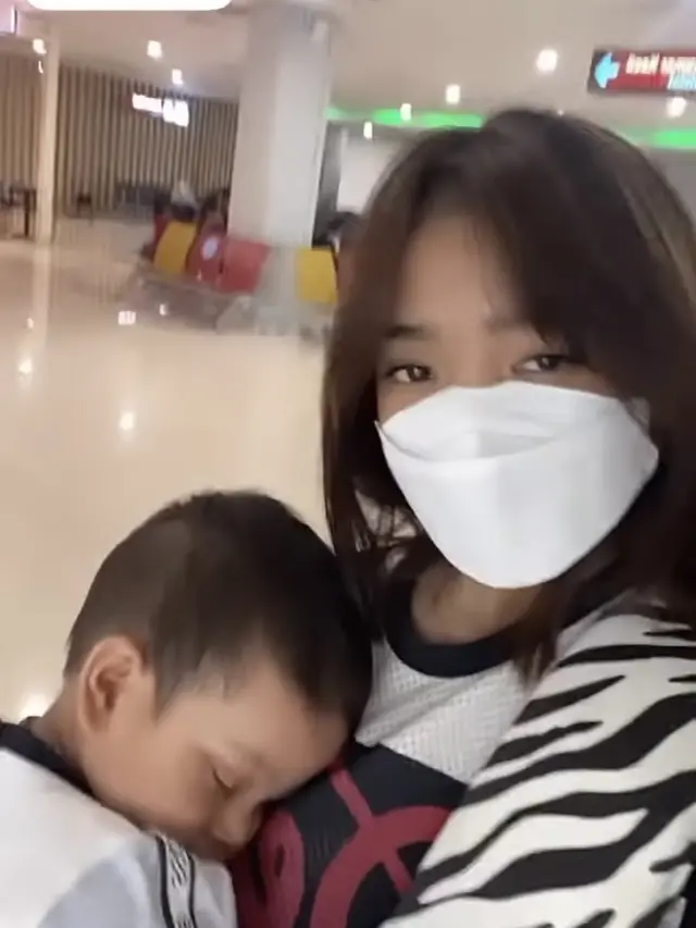 Fuji menggendong sang keponakan, Gala Sky di bandara dalam perjalanan pulang dari Bali ke Jakarta.