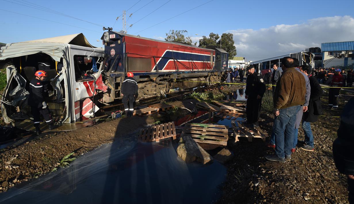 Tim penyelamat memeriksa kondisi sebuah bus yang dihantam kereta ketika melintasi rel dekat wilayah Sidi Fathallah, sekitar 10 km selatan Ibu Kota Tunisia, Rabu (28/12). Penyelidikan tengah dilakukan untuk mencari tahu apa yang terjadi. (Fethi Belaid/AFP)