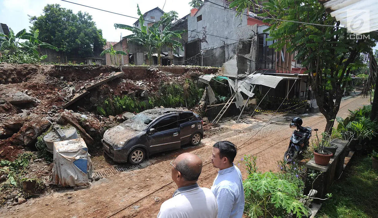 Warga menyaksikan longsor tembok perumahan Lereng Indah yang terjadi di Perumahan Lereng Bukit Indah, Pondok Cabe Udik, Pamulang,Tangerang Selatan, Senin (8/4). Tembok perumahan sepanjang 25 meter dan tinggi enam meter itu longsor kemarin sore, Minggu (7/4). (merdeka.com/Arie Basuki)