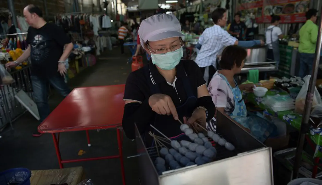 Seorang wanita mengenakan masker mempersiapkan makanan di pasar di Bangkok, Thailiand, (9/6/ 2015). Pemerintah Thailand mengumumkan bahwa seorang pria 75 tahun asal Oman positif terjangkit virus MERS.  (AFP PHOTO/Christophe Archambault)