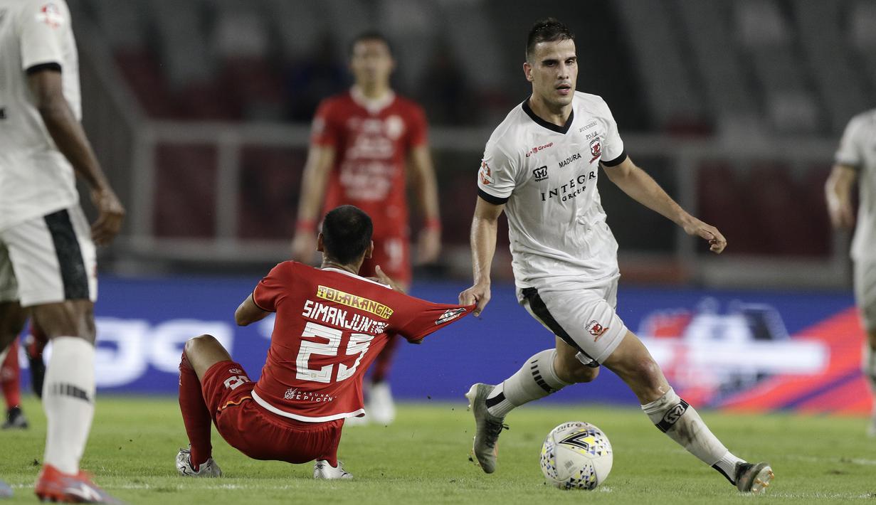 Gelandang Persija Jakarta, Riko Simanjutak, berebut bola dengan gelandang Madura United, Marchkho Merauje, pada laga Shopee Liga 1 di SUGBK, Jakarta, Jumat (13/12). Persija menang 4-0 atas Madura. (Bola.com/Yoppy Renato)