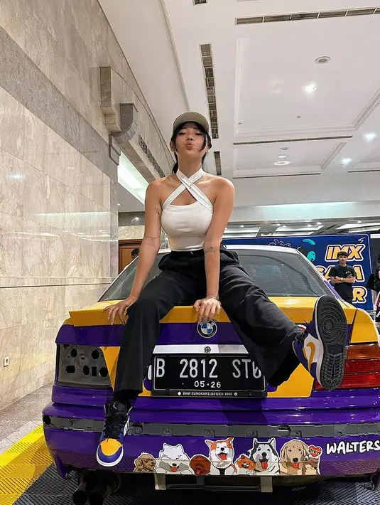 Selain hobi naik gunung, Wendy Walters juga memiliki hobi cukup ekstrem, yaitu drifting. Di sini, Wendy berpose di atas sebuah mobil mengenakan cross-neck tank top putih dipadu dengan celana panjang hitam, dan topi putih yang serasi. [Foto: Instagram/wendywalters]