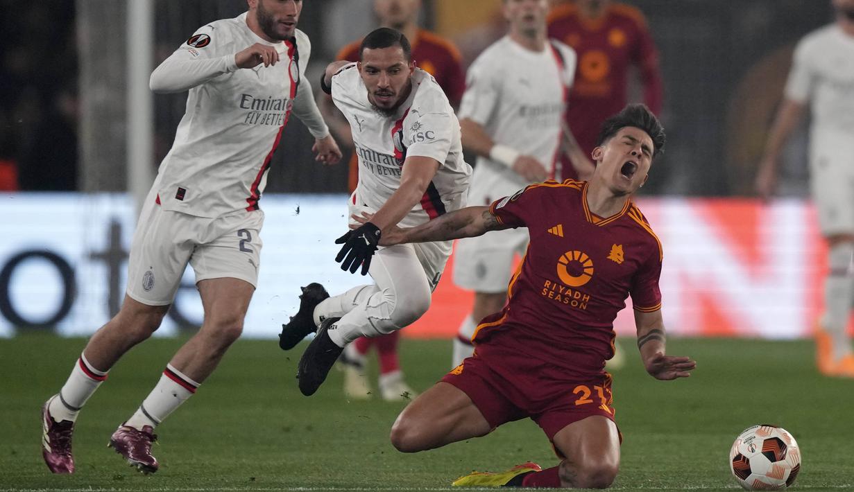 Pemain AS Roma, Paulo Dybala, terjatuh saat berusaha melewati pemain AC Milan, Ismael Bennacer, pada leg kedua perempat final Liga Europa di Stadion Olimpico, Roma, Jumat (19/4/2024). Giallorossi menang dengan skor 2-1. (AP Photo/Andrew Medichini)