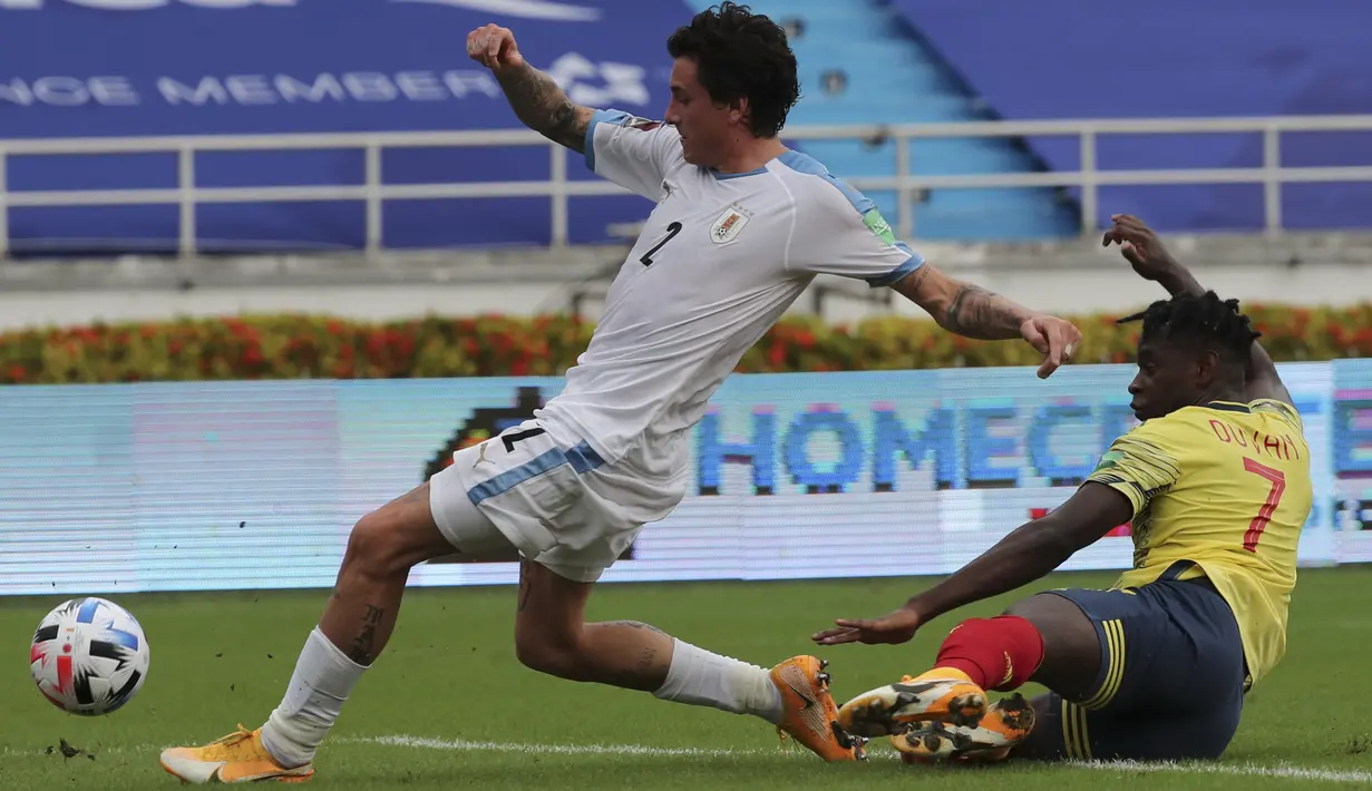 Penyerang Kolombia, Duvan Zapata berebut bola dengan bek Uruguay, Jose Gimenez dalam laga Kualifikasi Piala Dunia 2022 zona Amerika Selatan di stadion Metropolitano, Barranquilla, Jumat (13/11/2020). Uruguay mengalahkan  Kolombia 3-0. (AP Photo/Fernando Vergara)