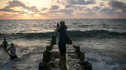 Seorang wanita mengambil gambar seorang pria yang tengah menikmati pantai Tel Aviv, Israel, Minggu (19/7/2015). Selama Idul Fitri, pemerintah Israel mengizinkan warga Palestina untuk berwisata di sepanjang garis pantai Mediterania. (REUTERS/Baz Ratner) 