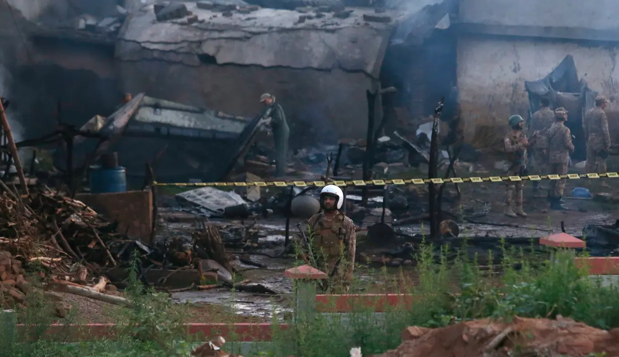 Pejabat militer Pakistan memeriksa lokasi kecelakaan pesawat di Rawalpindi, Pakistan, Selasa (30/7/2019). Kecelakaan menyebabkan 12 orang tewas dan memicu kebakaran besar yang melanda beberapa rumah. (AP Photo/Anjum Naveed)