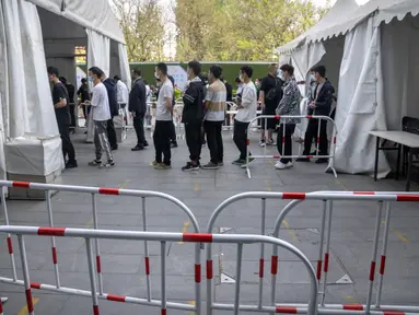 Orang-orang mengantre untuk tes COVID-19 di fasilitas pengujian virus corona di Beijing, China, Sabtu (23/4/2022). Beijing dalam keadaan waspada setelah 10 siswa sekolah menengah dinyatakan positif COVID-19 pada hari Jumat, yang menurut pejabat kota sebagai putaran awal pengujian. (AP Photo/Mark Schiefelbein)