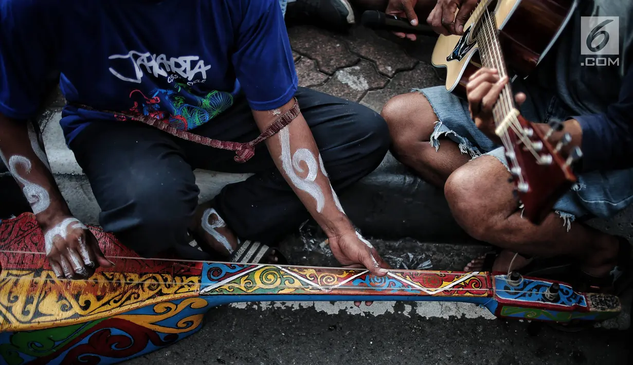 Eks pekerja PT Freeport Indonesia bermain musik saat menggelar aksi selama Car Free Day di kawasan Bunderan HI, Jakarta, Minggu (30/12). Aksi tersebut dilakukan protes mereka ke pemerintah. (Liputan6.com/Faizal Fanani)