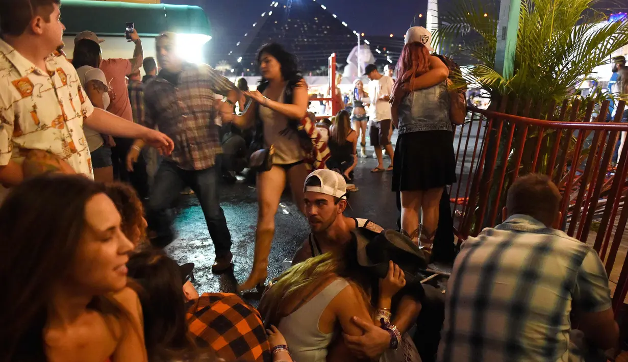 Pengunjung berlindung saat festival musik Route 91 Harvest country setelah aksi penembakan di Las Vegas, Nevada (1/10). Aparat Kepolisian di Las Vegas, Nevada, Amerika Serikat masih memburu seorang pelaku penembakan. (David Becker/Getty Images/AFP)
