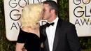 Penyanyi Lady Gaga dan sang tunangan, Taylor Kinney saling berciuman dengan mesra saat ditengah-tengah sesi foto ajang penghargaan film tahunan, Golden Globes 2016 di Beverly Hilton Hotel, California, Minggu (10/1). (Jason Merritt/Getty Images/AFP)