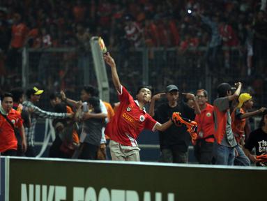Suporter Persija melempari petugas kepolisian saat terlibat kericuhan pada laga lanjutan Torabika Soccer Championship presented by IM3 Ooredoo antara Persija melawan Sriwijaya FC diStadion GBK Jakarta, Jumat (24/6). (Liputan6.com/Helmi Fithriansyah)