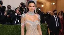 Kendall Jenner tampil bergaya ‘naked’ dalam balutan sheer gown bertabur kristal berkilau rancangan Givenchy. Penampilannya yang glamor tersebut diperlengkap dengan kalung choker besar. Model 25 tahun ini menjaga rambutnya tetap sederhana dengan sanggul rendah. (Instagram/_metgala2021).