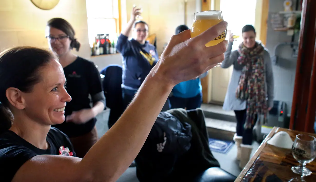 Seorang wanita mengangkat gelas bersulang saat meminum bir yang dibuatnya di tempat pembuatan bir di Black Pond Brews, Danielson (4/3). (AP Photo / Steven Senne)