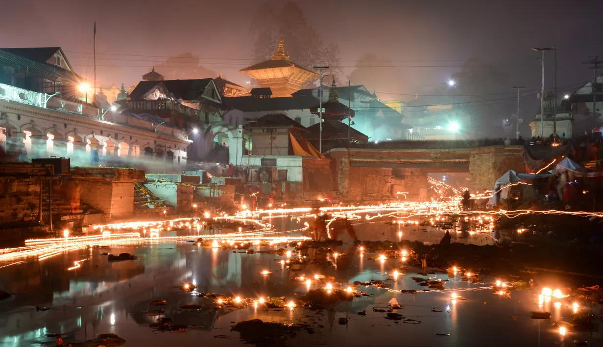 Lampu minyak menerangi sungai selama festival Bala Chaturdashi di Kuil Pashupatinath di Kathmandu (6/12). Festival Bala Chaturdashi ini dirayakan untuk mengenang anggota keluarga yang telah tiada. (AFP Photo/Prakash Mathema)