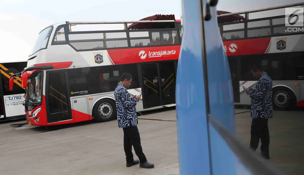 Petugas berada di dekat bus transjakarta yang akan digunakan untuk pawai kemenangan tim Persija Jakarta di kantor PT Transjakarta, Cawang, Kamis (13/12). Bus tersebut akan digunakan untuk pawai kemenangan Persija. (Liputan6.com/Immanuel Antonius)