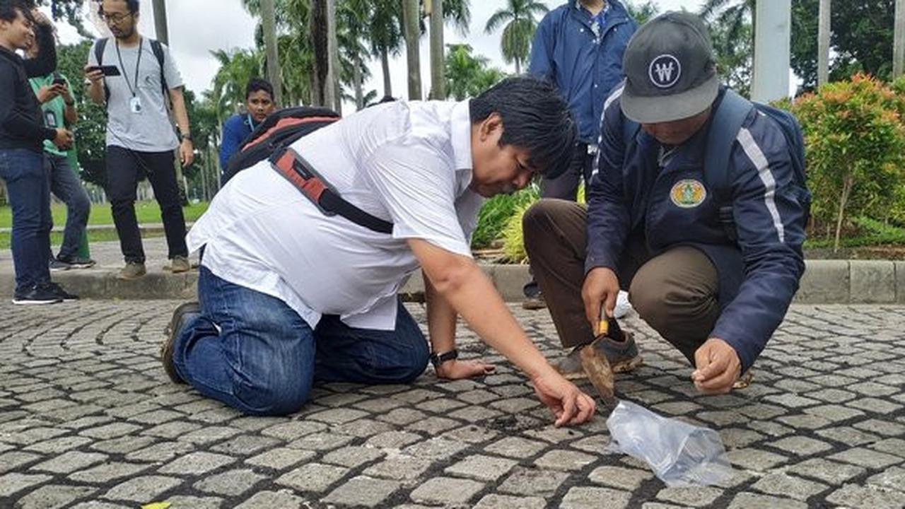 Petugas memperhatikan bekas aspal di Monas. (Merdeka.com/Yunita Amalia)