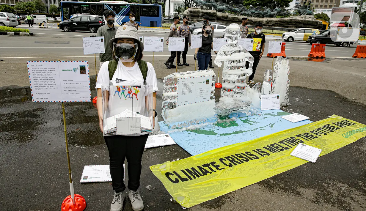 Aksi berupa patung es dalam pengantaran 1000 kartu pos oleh aktivis Greenpeace kepada Presiden Joko Widodo di kawasan Monumen Patung Kuda, Jakarta, Rabu (10/11/2021). Kartu pos itu berisikan agar pemerintah melihat dampak perubahan iklim terhadap ekosistem di sekitar. (Liputan6.com/Faizal Fanani)