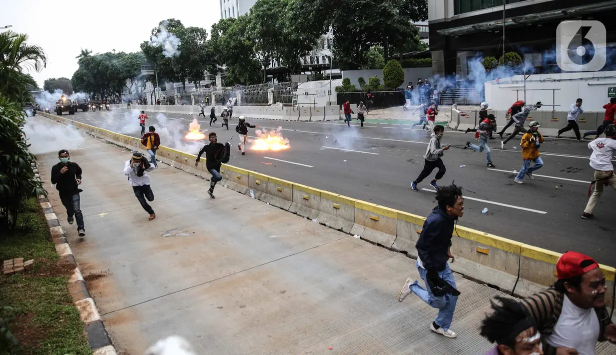 Pengunjuk rasa tolak UU Cipta Kerja bentrok dengan polisi di sekitar Patung Kuda, Jakarta Pusat, Selasa (13/10/2020). Gas air mata ditembakkan ke arah pendemo yang melakukan perlawanan dengan melempar batu dan pecahan kaca. (Liputan6.com/Faizal Fanani)
