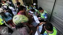 Petugas menulis surat tilang pada operasi lintas di Abu Bakar Ali,Yogyakarta, (19/5). Operasi ini untuk menekan angka kecelakaan, petugas memberikan surat tilang di tempat kepada pelanggar lalu lintas. (Liputan6.com/Boy Harjanto)