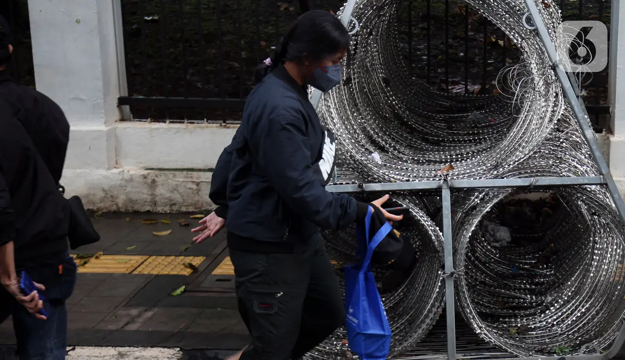 Pejalan kaki berjalan menghindari kawat berduri yang berada di trotoar Jalan Asia Afrika, Jakarta Pusat, Selasa (28/12/2021). Kawat berduri yang berada di trotoar tersebut sangat mengganggu para pejalan kaki yang melintas. (Liputan6.com/Johan Tallo)