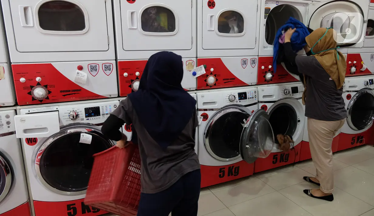 Pekerja memasukkan pakaian ke mesin cuci di gerai jasa layanan laundry, kawasan Kemang, Jakarta, Rabu (25/11/2020). Sejak tiga bulan terakhir omset mereka kembali membaik dan mengalami peningkatan sebesar 20 hingga 30 persen. (Liputan6.com/Herman Zakharia)