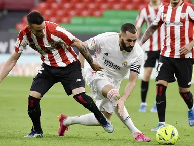 Striker Real Madrid, Karim Benzema, berusaha melewati pemain Athletic Bilbao, Alex Berenguer, pada laga Liga Spanyol di Stadion San Mames, Minggu (16/5/2021). Real Madrid menang dengan skor 1-0. (AP Photo/Alvaro Barrientos)