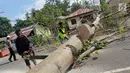 Warga memotong pohon berumur puluhan tahun yang tumbang di Jalan Trans Sulawesi, Limboto, Gorontalo, Senin, (21/1). Kemacetan akibat kejadian tersebut pun  tak terhindarkan. (Liputan6.com/Arfandi Ibrahim)