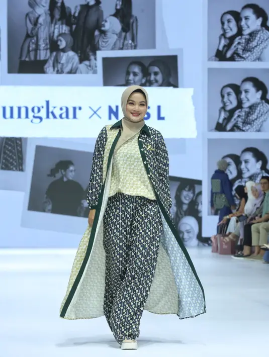 Pada runway, Titi mengenakan setelan longgar dengan motif bold yang memberikan kesan modern dan stylish. [Dok/Fimela/Adrian Utama P].