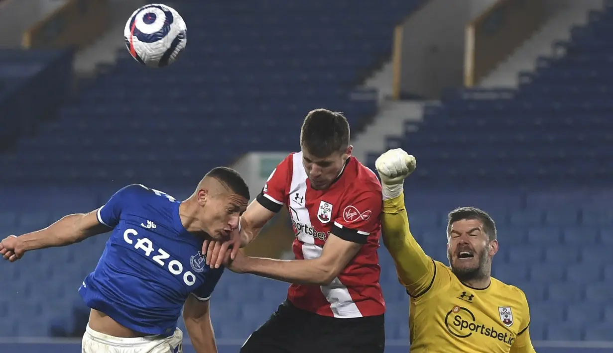 Kiper Southampton, Fraser Forster (kanan) meninju bola dari ancaman striker Everton, Richarlison (kiri) dalam laga lanjutan Liga Inggris 2020/21 pekan ke-26 di Goodison Park, Liverpool, Senin (1/3/2021). Southampton kalah 0-1 dari Everton. (AP/Gareth Copley/Pool)