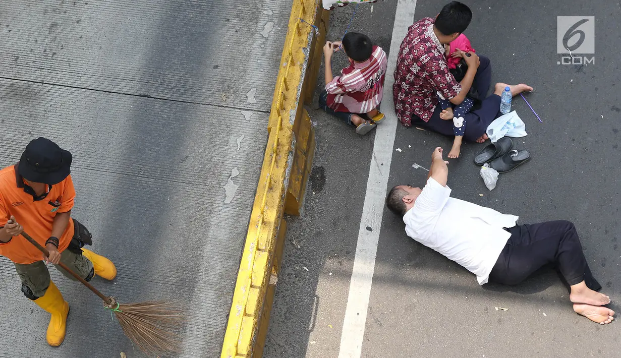 Warga beristirahat saat pasukan oranye membersihkan sampah selama Car free day (CFD) di Jalan Warung Jati Barat, Jakarta, Minggu (17/9). CFD kembali digelar untuk kedua kalinya di kawasan Mampang Prapatan hingga Pejaten. (Liputan6.com/Immanuel Antonius)
