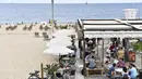 Orang-orang duduk di bar teras di Pantai Bogatell di Barcelona, Minggu (6/6/2021). Spanyol akan mengizinkan semua pelancong yang divaksinasi untuk mengunjungi negara itu mulai 7 Juni, dengan tujuan kembali menghidupkan industri perjalanan yang terpukul pandemi Covid-19. (Pau BARRENA/AFP)