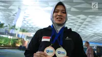 Atlet panjat tebing putri Indonesia, Aries Susanti Rahayumenunjukkan medali usai penyambutan di Bandara Soetta, Tangerang, Rabu (16/5). Aries berhasil mengalahkan Elena Timofeeva (Rusia) dengan waktu 7,51 detik. (Liputan6.com/Helmi Fithriansyah)