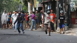 Massa melempar batu ke arah aparat keamanan saat terjadi bentrok di kawasan Slipi, Jakarta Barat, Rabu (22/5/2019). Massa yang terlibat kerusuhan tarpantau sebagian besar masih berusia remaja. (Liputan6.com/Gempur Muhammad Surya)