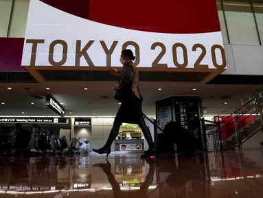 Seorang pramugari berjalan di depan layar besar Olimpiade Tokyo 2020 di Bandara Internasional Narita, Tokyo, Kamis (15/7/2021). Upacara pembukaan Olimpiade Tokyo akan digelar pada 23 Juli 2021 dan berakhir pada 8 Agustus 2021. (AP Photo/Kiichiro Sato)