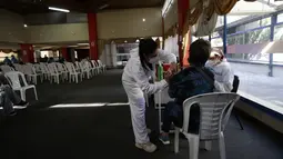 Seorang perempuan mendapat suntikan vaksin COVID-19, di Quito, Ekuador, Kamis (24/12/2021). Pemerintah Ekuador telah menyatakan vaksinasi COVID-19 wajib setelah meningkatnya infeksi dan munculnya varian baru virus corona. (AP Photo/Carlos Noriega)
