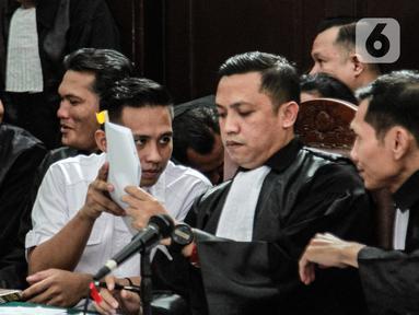 Terdakwa Richard Elieze berdiskusi dengan kuasa hukumnya disela sidang lanjutan pemeriksaan saksi kasus pembunuhan berencana Brigadir Yosua Hutabarat atau Brigadir J di Pengadilan Negeri Jakarta Selatan, Senin (7/11/2022). Richard Eliezer dan Ricky Rizal yang merupakan mantan ajudan Ferdy Sambo serta Kuat Ma'ruf, sopir keluarga Sambo duduk bersama di kursi terdakwa pada hari ini. (Liputan6.com/Johan Tallo)