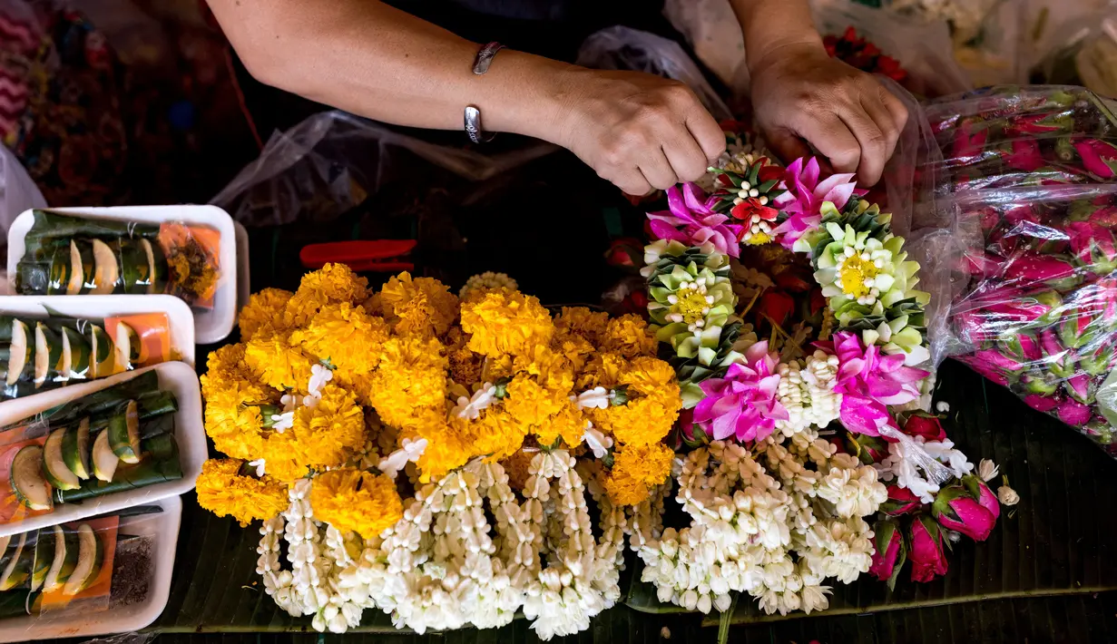 Seorang wanita menyiapkan karangan bunga menjelang Loy Krathong di pasar bunga Pak Khlong Talat, Bangkok, Kamis (18/11/2021). Bulan November ini Thailand akan mengadakan festival Loy Krathong di mana warga menghanyutkan keranjang berisi bunga dan lilin di sungai atau danau. (Jack TAYLOR/AFP)