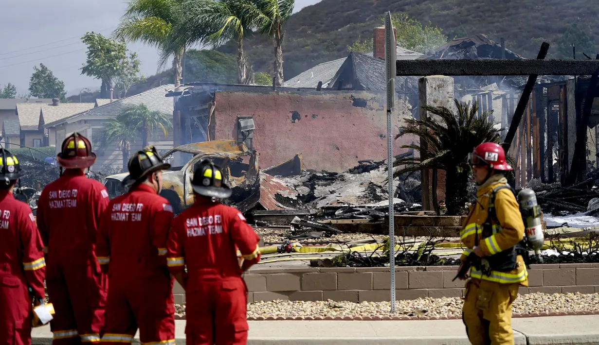 Petugas pemadam kebakaran berada di lokasi jatuhnya sebuah pesawat kecil jatuh di Santee, California, Senin (11/10/2021). Puing-puing dilaporkan berserakan di blok perumahan itu dan sedikitnya 10 rumah kini dalam keadaan padam listrik karena evakuasi. (AP Photo/Gregory Bull)