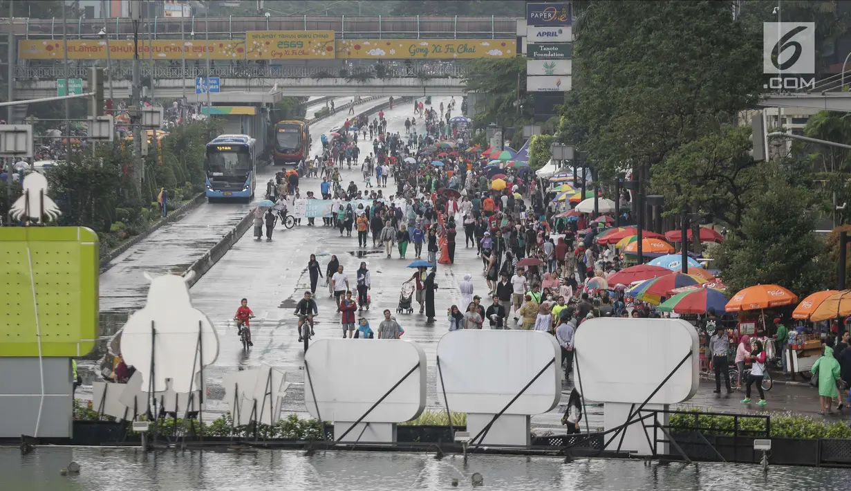 Sejumlah warga memadati kawasan Bunderan HI saat kegiatan rutin hari bebas kendaraan bermotor atau car free day (CFD), Jakarta, Minggu (4/2). Walaupun gerimis mengguyur kawasan Bunderan HI tetap ramai oleh aktivitas warga. (Liputan6.com/Faizal Fanani)
