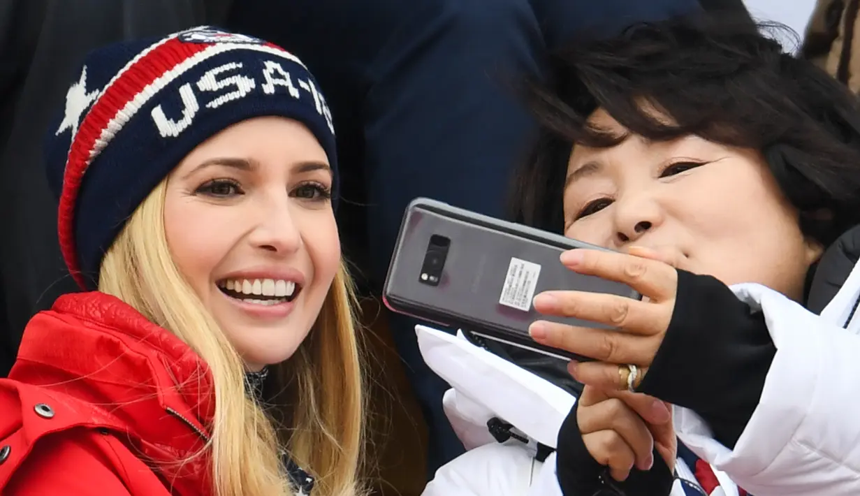 Putri Presiden AS Donald Trump, Ivanka Trump (kiri) berpose dengan istri Presiden Korea Moon Jae-in, Kim Jung-sook (kanan) saat menonton snowboard pria pada Olimpiade Musim Dingin Pyeongchang 2018, Korea Selatan, Sabtu (24/2). (FRANCK FIFE/AFP)