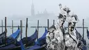 Dua orang peserta berpose di Piazza San Marco saat mengikuti Karnaval Venesia, Italia, Sabtu (30/1). Dalam acara tahunan ini, peserta mengenakan kostum ala Venesia abad ke-18 dan topeng-topeng unik menutupi wajah (REUTERS/Alessandro Bianchi)