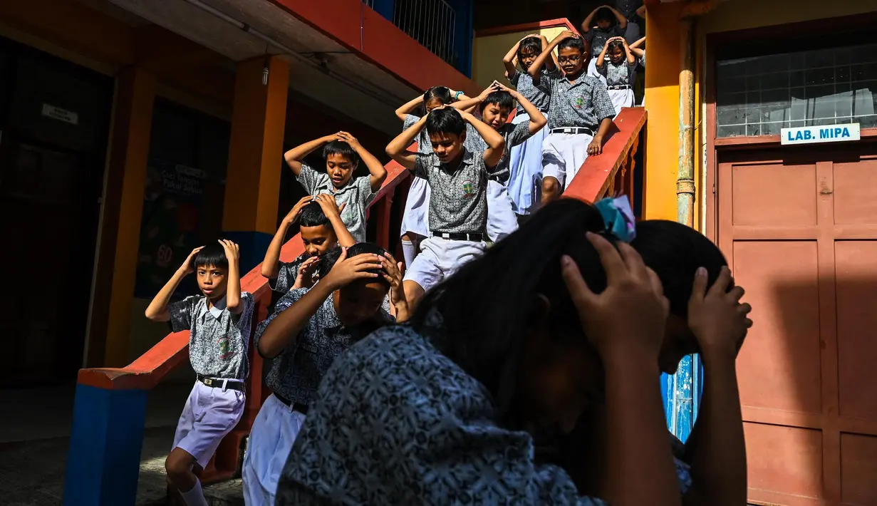 Para siswa melakukan simulasi terkait apa saja yang harus dilakukan ketika sewaktu-waktu terjadi bencana gempa bumi dan tsunami. (CHAIDEER MAHYUDDIN/AFP)