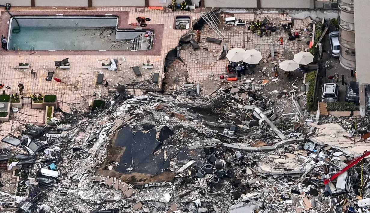 Pemandangan udara ini, menunjukkan tim penyelamat dan pencarian berada di lokasi runtuhnya sebagian menara apartemen tepi laut di Surfside, utara Miami, Kamis (24/6/2021). Para pejabat tidak tahu berapa banyak yang berada di menara ketika jatuh. (CHANDAN KHANNA / AFP)