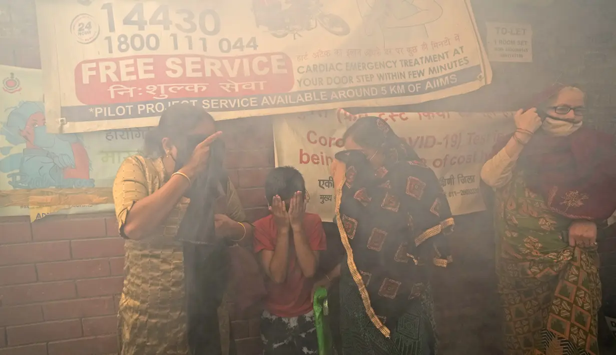 Sebuah keluarga berjalan melewati asap dari fogging di daerah padat penduduk di New Delhi, India, Rabu (27/10/2021). New Delhi telah melaporkan ratusan kasus demam berdarah, dengan lebih dari 200 kasus baru dalam seminggu terakhir, menurut laporan yang dirilis pada Senin. (AP Photo/Manish Swarup)
